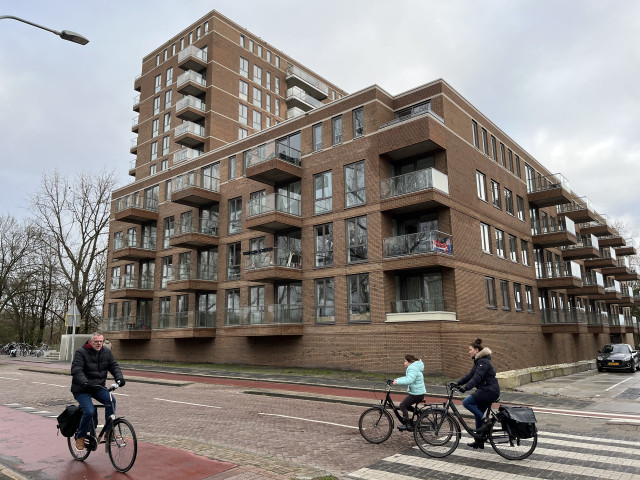 Foto van het gebouw de Brugwachter in de Korrewegwijk. Op de foto zie je tevens 3 mensen op de fiets.