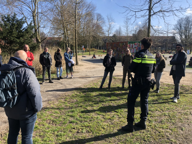 Een groep mensen praat met de wijkagent in een park in de Oosterparkwijk
