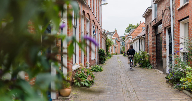 Foto van een jongedame fietsend door een smal straatje in de wijk Oosterpoort in Groningen