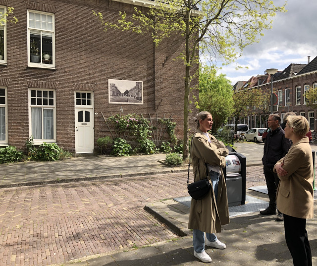Op de foto zien we rechts in beeld drie mensen staan die met elkaar in gesprek zijn. Deze foto is gemaakt in de Korrewegwijk. Op de achtergrond zien we rijtjeshuizen.